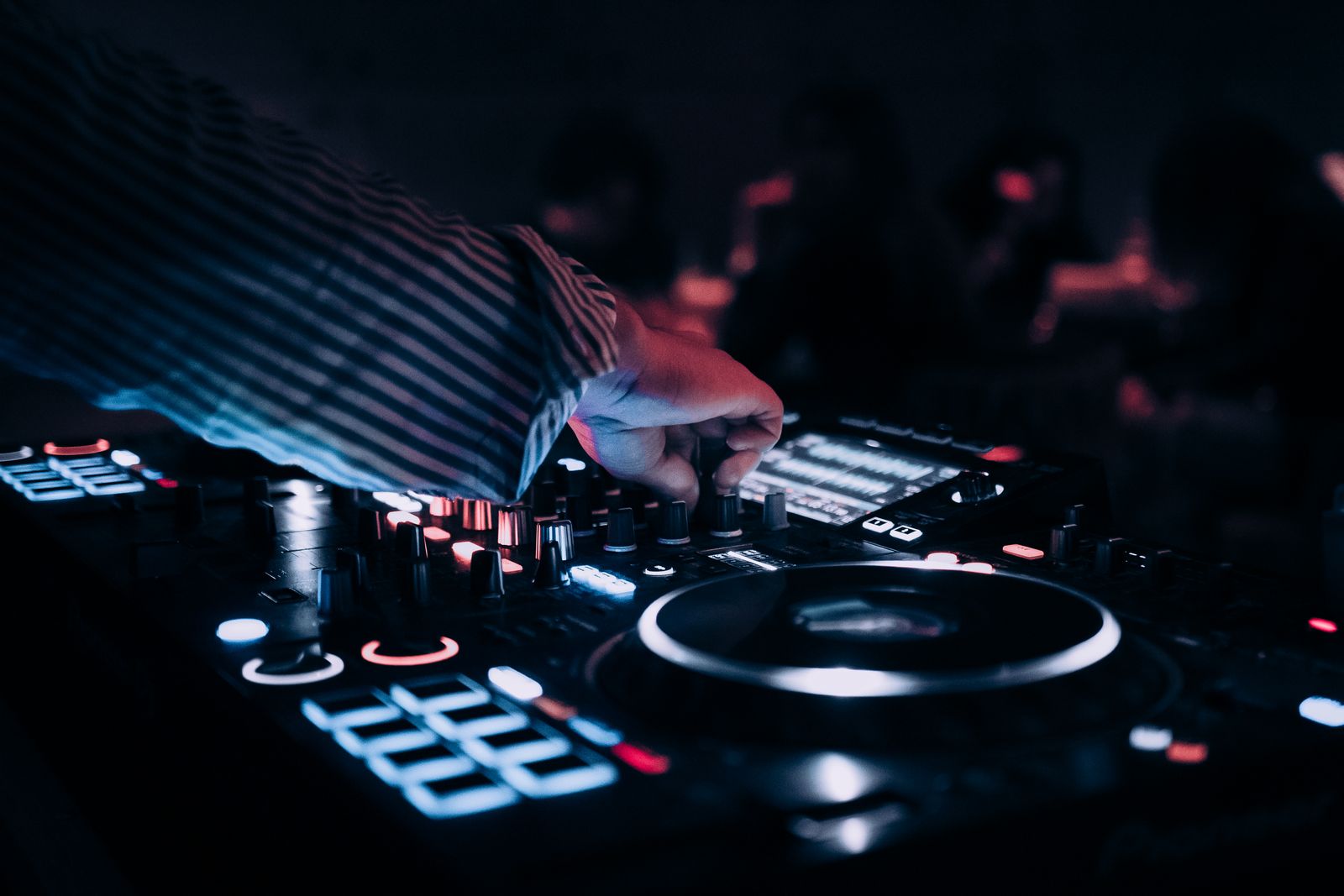 DJ am beleuchteten Mischpult während eines Sets